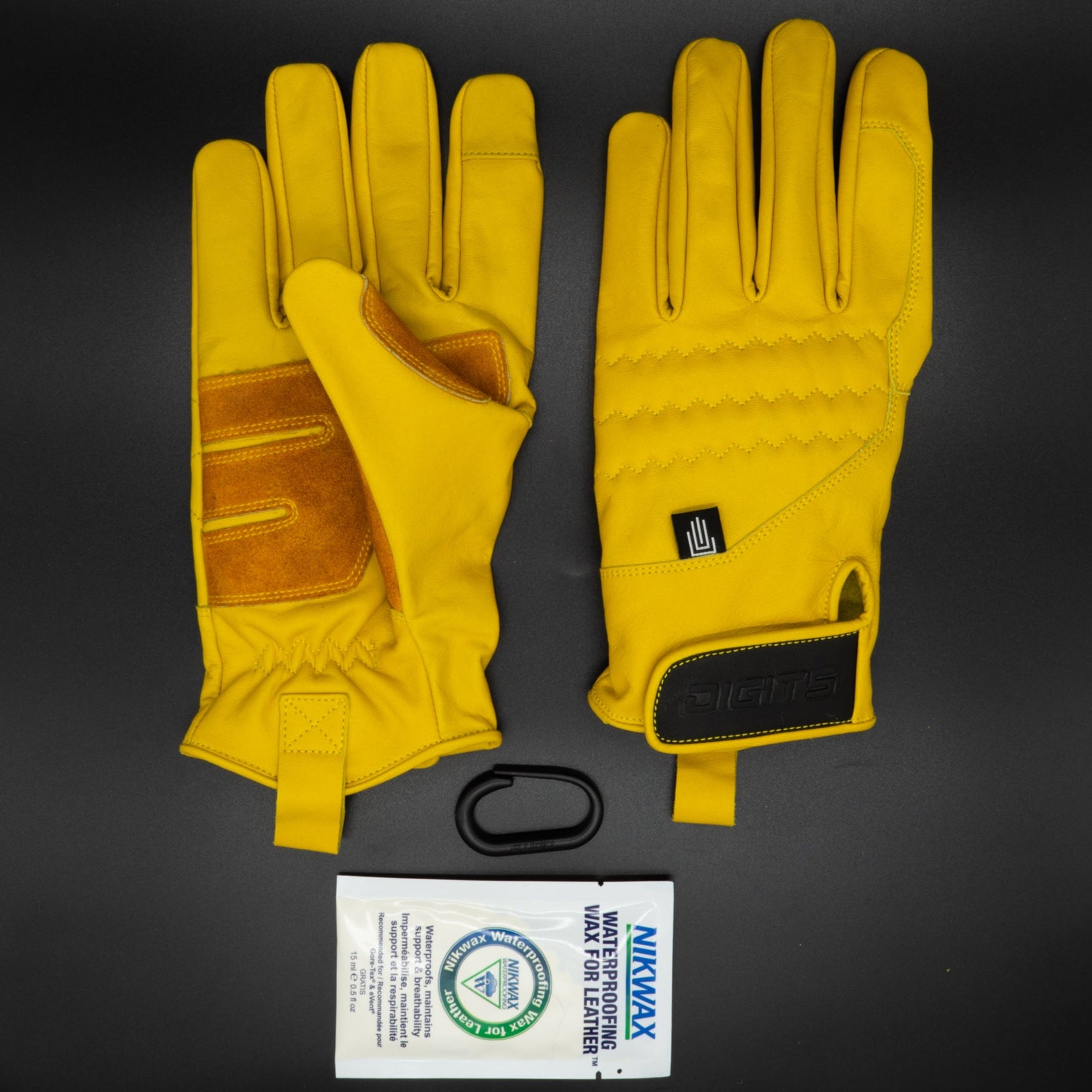 A pair of yellow, non-insulated leather work gloves with extended cuffs and Velcro wrist closures, displayed palm-up with a company logo on the Velcro strap, alongside a package of Nikwax leather waterproofing.