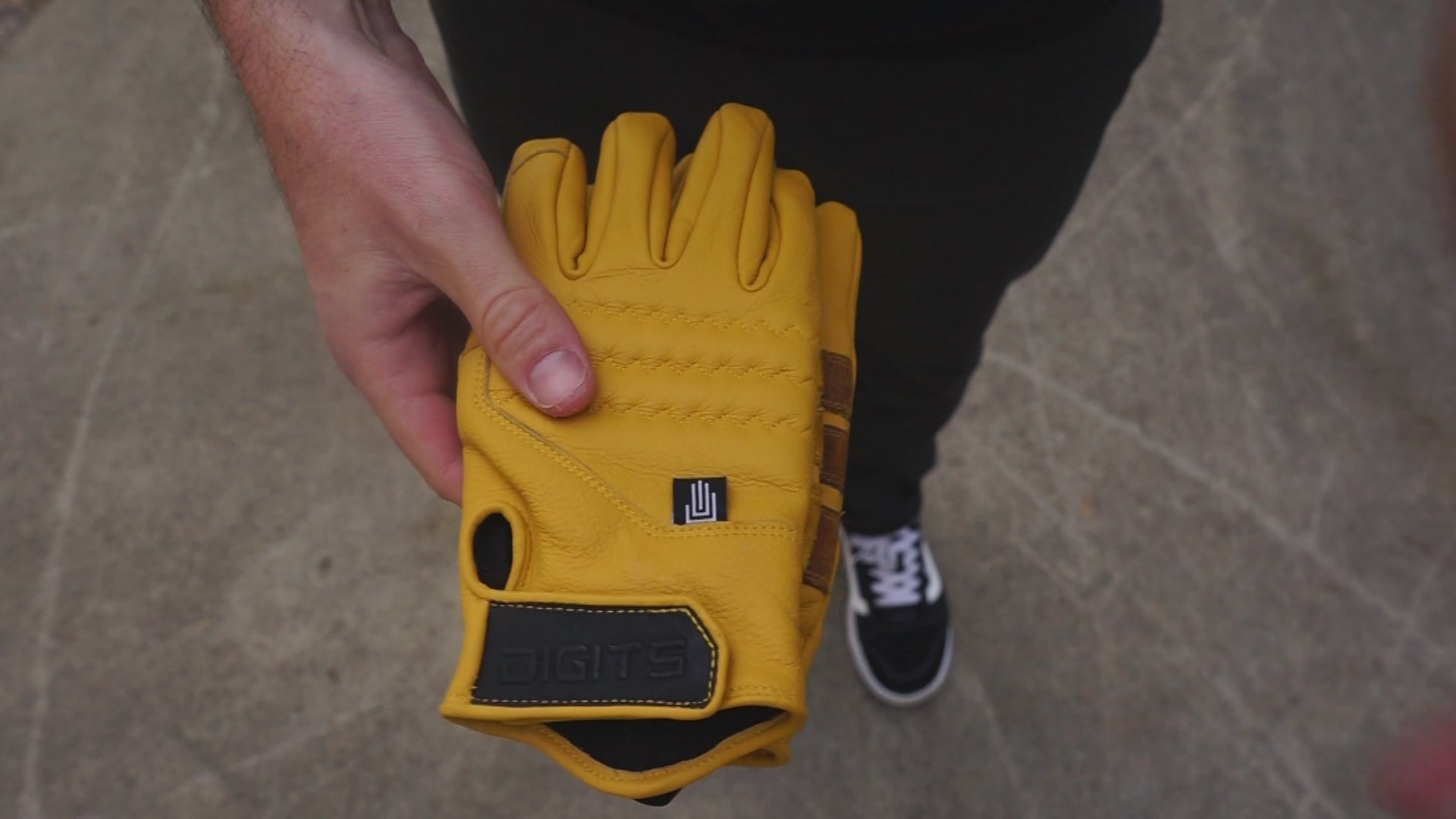 Load video: A worker slides on Digits Workwear non-insulated leather gloves, adjusting the fit. Close-up details highlight the durable leather, reinforced stitching, and flexible design, showcasing the gloves&#39; grip, protection, and comfort.